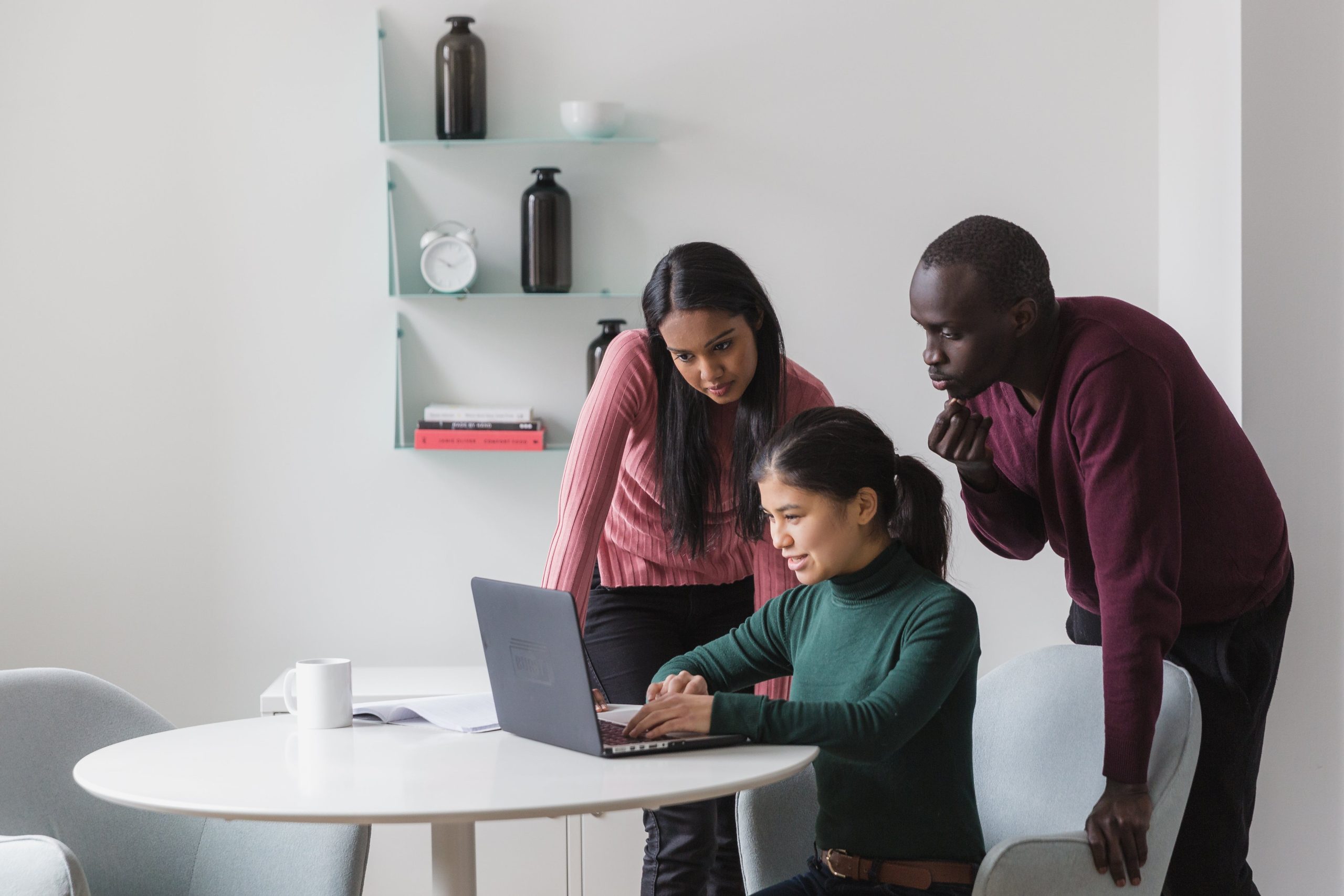 Three people looking at a shared computer